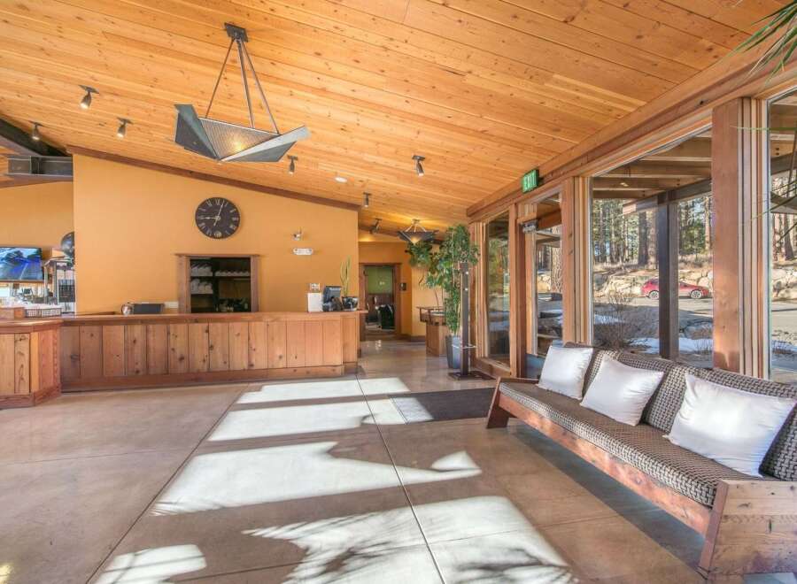 Experience a warm welcome in this inviting lobby featuring a rustic wooden reception desk and a comfortable seating area.