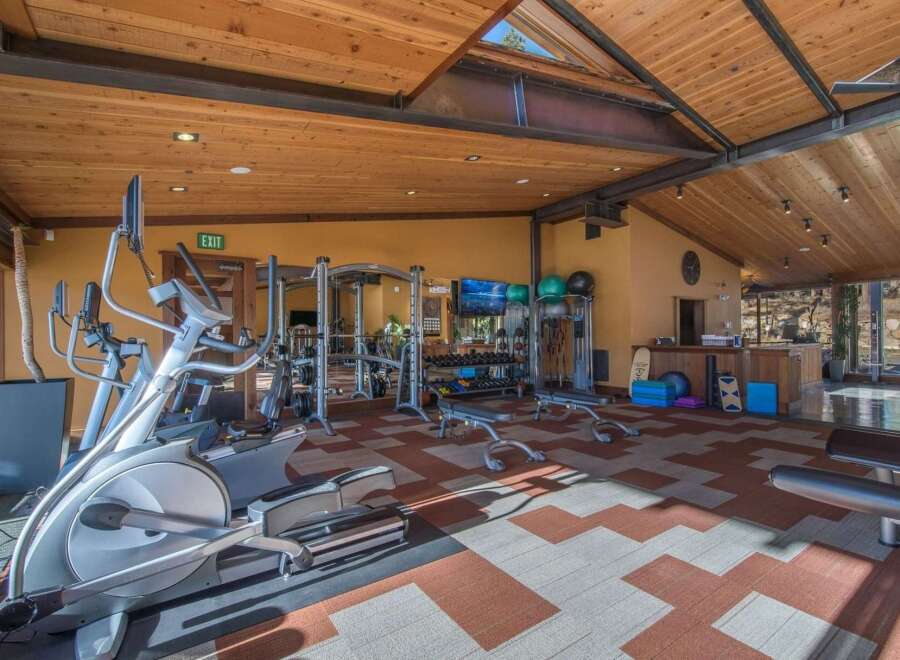 Elevate your fitness routine in this well-equipped home gym, featuring a variety of cardio machines like ellipticals and a full-scale weight training station.