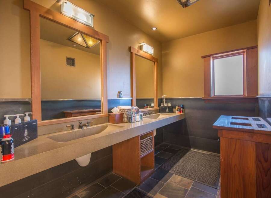 This spacious bathroom features a double vanity with integrated sinks and wooden framed mirrors, perfect for shared use.
