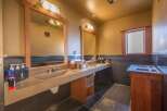This spacious bathroom features a double vanity with integrated sinks and wooden framed mirrors, perfect for shared use.