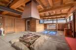 Experience ultimate relaxation in this unique indoor/outdoor spa area, featuring a covered hot tub with a protective blue cover and a modern metal fire pit structure.