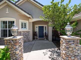 Welcome guests to this charming home with a striking stone-accented entrance, featuring elegant lamp posts and a welcoming dark blue front door.
