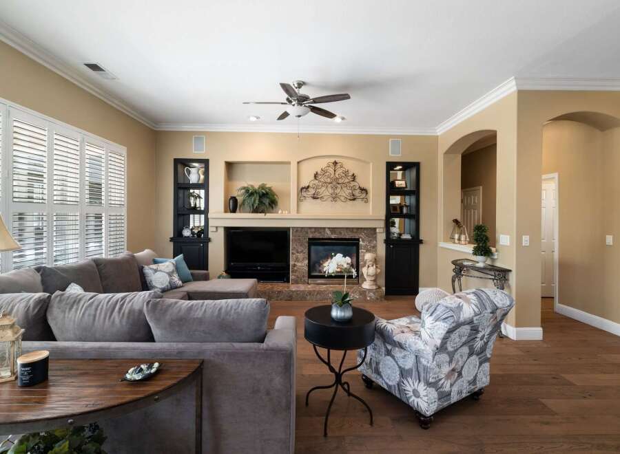 Experience luxury living in this beautifully appointed living room, featuring a grand fireplace with intricate stonework and a decorative metal accent above.
