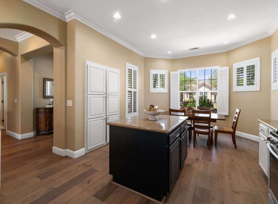 This spacious kitchen boasts a large island with granite countertops, perfect for meal preparation and casual dining.