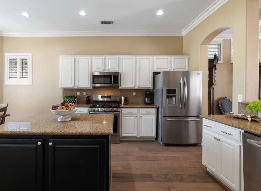 This spacious kitchen boasts elegant white cabinetry and granite countertops, perfect for any home chef.
