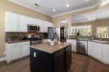 This spacious kitchen features white cabinetry, granite countertops, and a large island with a dark wood base.