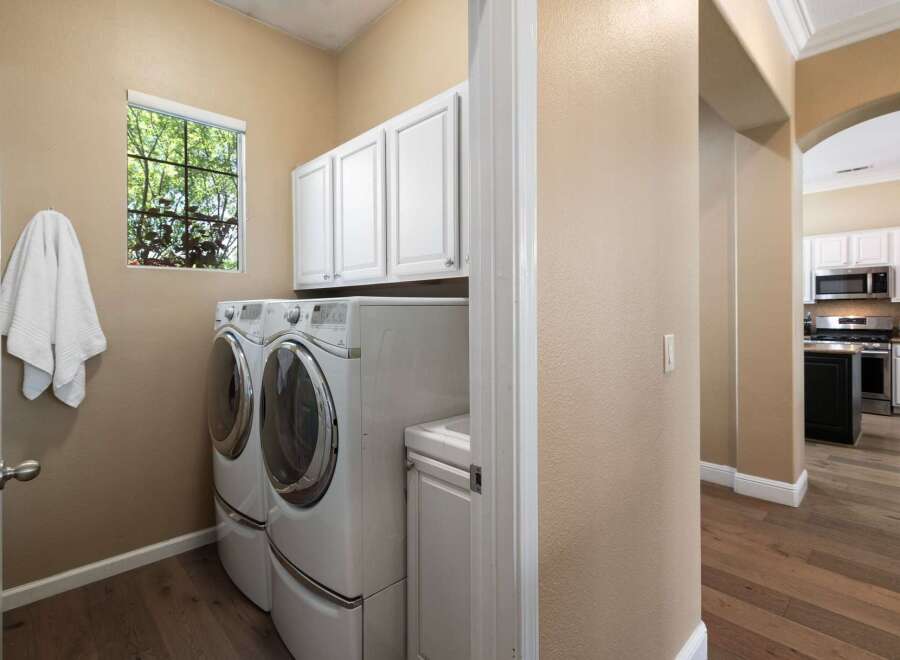 This spacious laundry room features a stacked washer and dryer set, complemented by ample white cabinetry for storage.