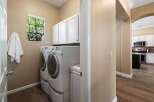 This spacious laundry room features a stacked washer and dryer set, complemented by ample white cabinetry for storage.