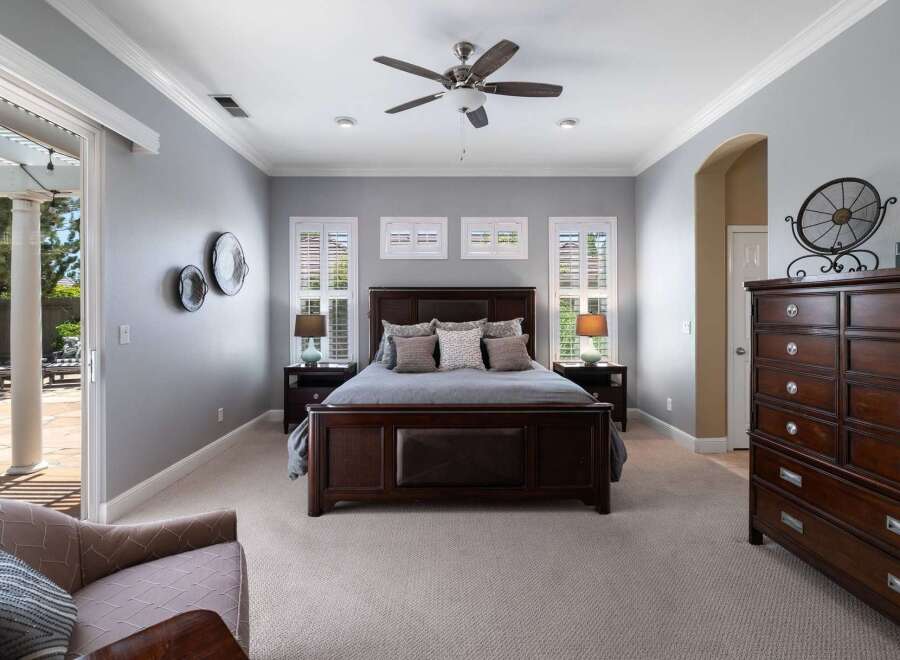Experience luxury in this master bedroom featuring a grand dark wood bed with plush bedding and accent pillows.
