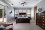 Experience luxury in this master bedroom featuring a grand dark wood bed with plush bedding and accent pillows.
