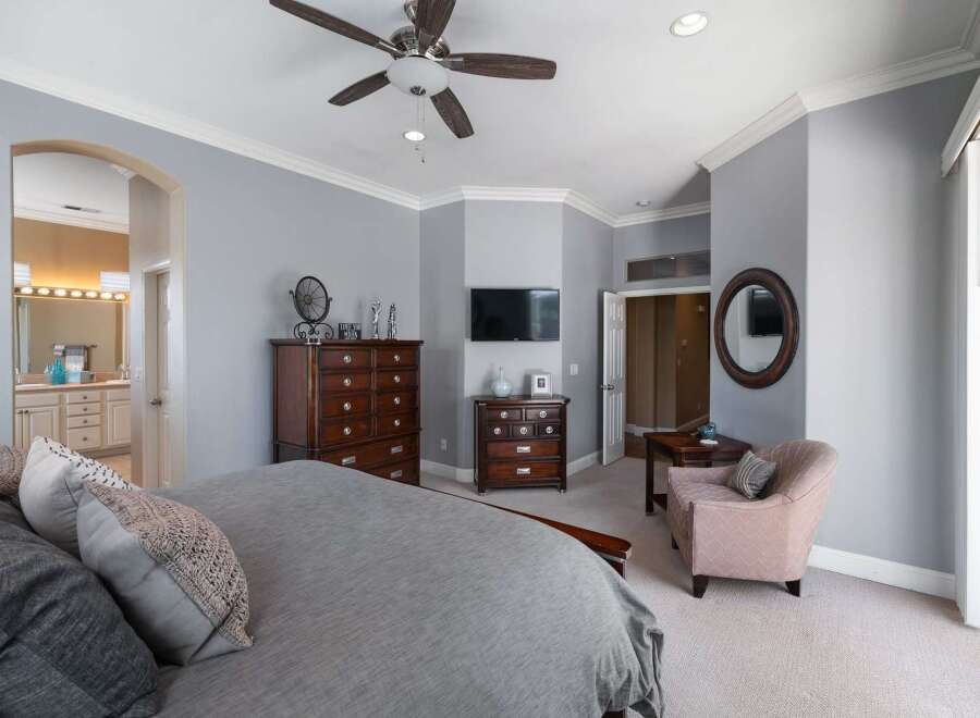Experience luxury in this master bedroom, featuring a spacious king-sized bed with plush bedding and elegant decorative pillows.