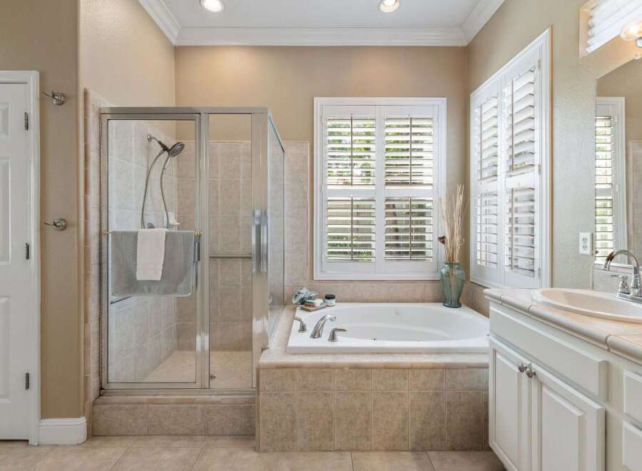 This spacious bathroom features a luxurious soaking tub with a tiled surround, perfect for unwinding after a long day.