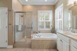 This spacious bathroom features a luxurious soaking tub with a tiled surround, perfect for unwinding after a long day.