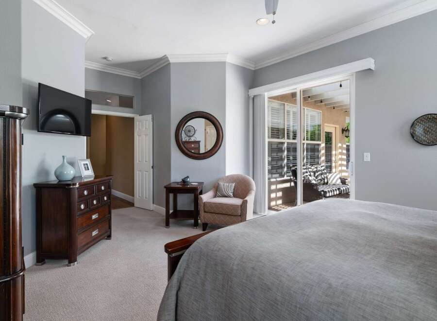 This spacious master bedroom offers a tranquil retreat with a large sliding glass door that opens to a private patio, perfect for enjoying the outdoors.