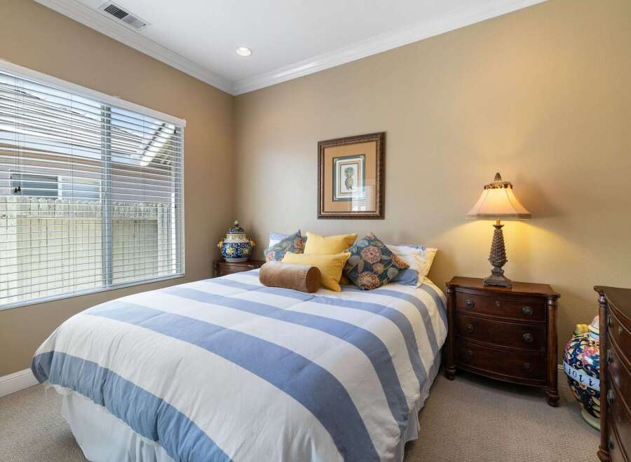 This charming bedroom features a comfortable queen-size bed adorned with a classic blue and white striped comforter and plush decorative pillows.