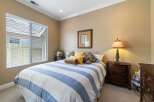 This charming bedroom features a comfortable queen-size bed adorned with a classic blue and white striped comforter and plush decorative pillows.