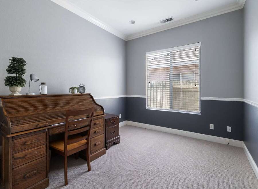 This home office features a classic wooden roll-top desk with ample storage and a matching chair, perfect for productivity.