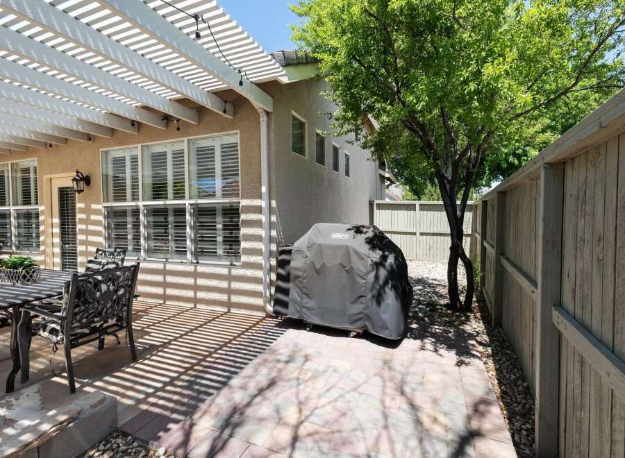 Enjoy outdoor living with this charming patio featuring a white pergola providing ample shade.
