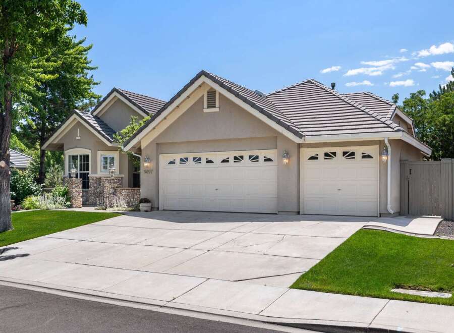 This charming single-family home features a welcoming facade with a stone-accented entrance and a spacious three-car garage.