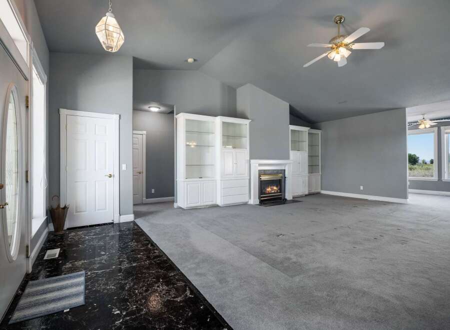 Step into this spacious living area featuring a cozy fireplace and elegant built-in shelving.