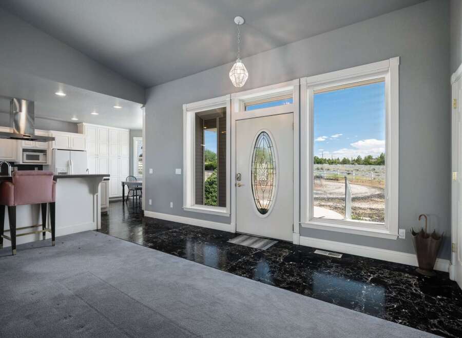 Step into a grand entryway featuring a stunning glass-paned front door and expansive windows that flood the space with natural light.
