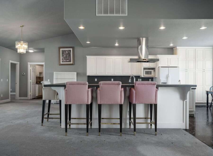This spacious kitchen features a large island with pink upholstered bar stools, perfect for casual dining and entertaining.