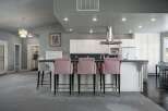 This spacious kitchen features a large island with pink upholstered bar stools, perfect for casual dining and entertaining.