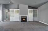 This spacious living room features a cozy fireplace as the focal point, flanked by elegant white built-in display cabinets with glass doors.