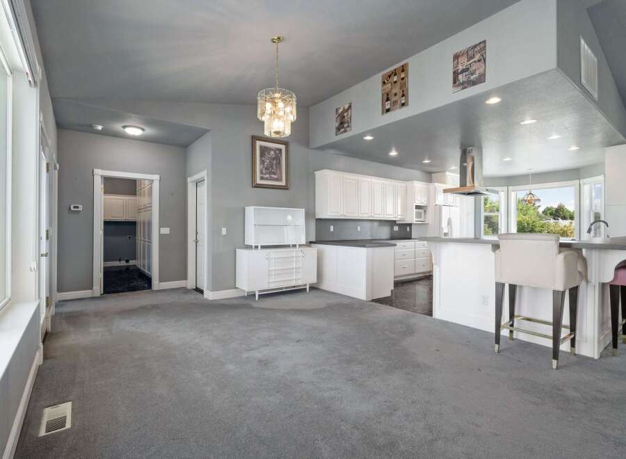 Discover this spacious open-concept living area, perfect for entertaining, featuring a modern kitchen with ample white cabinetry and a large island.