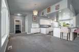 Discover this spacious open-concept living area, perfect for entertaining, featuring a modern kitchen with ample white cabinetry and a large island.