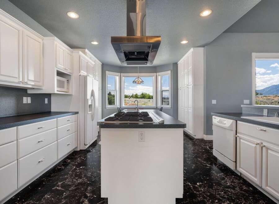 Experience culinary excellence in this spacious kitchen featuring a central island with a gas cooktop and a sleek stainless steel range hood.