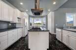 Experience culinary excellence in this spacious kitchen featuring a central island with a gas cooktop and a sleek stainless steel range hood.