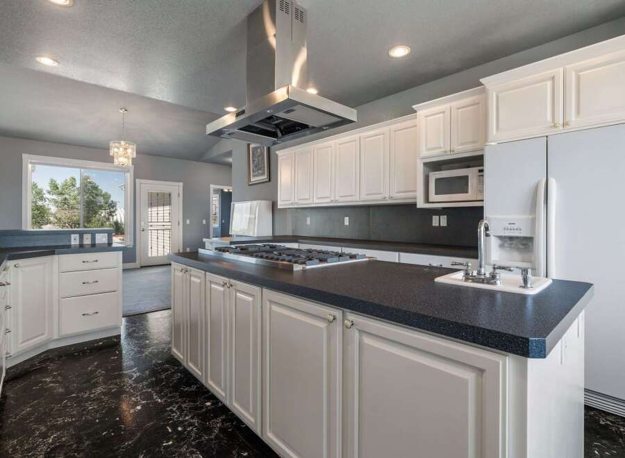 This spacious kitchen boasts a large central island with a gas stovetop, perfect for culinary enthusiasts.