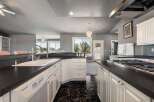 This spacious kitchen features a large sink, a gas range, and ample cabinet space, perfect for any home chef.