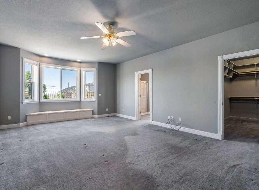 This spacious bedroom features a large bay window with a built-in bench, perfect for enjoying the natural light and scenic views.