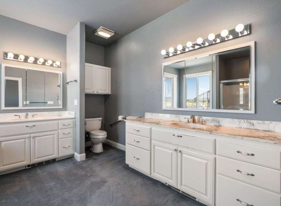 This spacious bathroom features a double vanity with ample counter space and storage, perfect for any household.