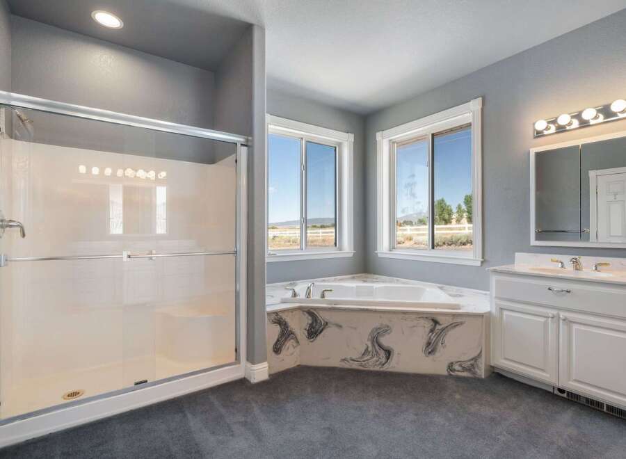 Indulge in relaxation in this spacious master bathroom, featuring a luxurious corner soaking tub with a stunning marble surround.