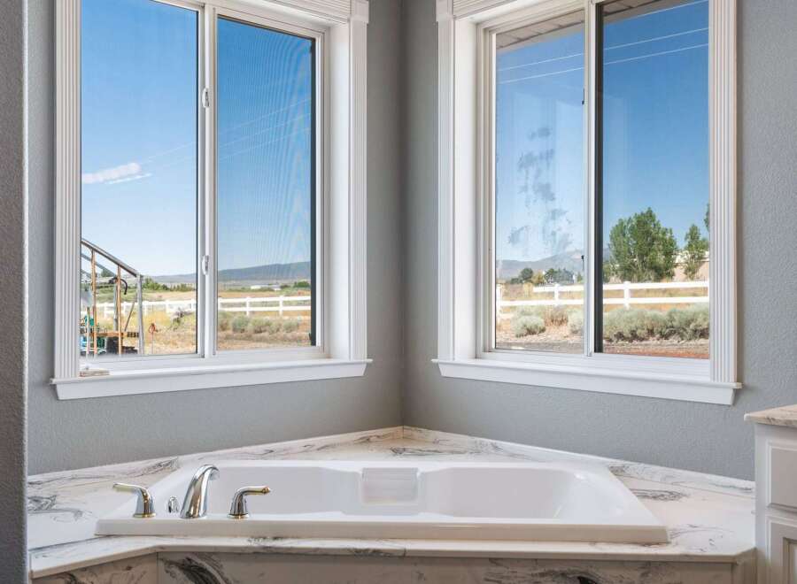 Experience tranquility in this luxurious bathroom featuring a spacious corner bathtub with stunning views of the surrounding landscape.
