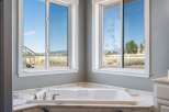 Experience tranquility in this luxurious bathroom featuring a spacious corner bathtub with stunning views of the surrounding landscape.