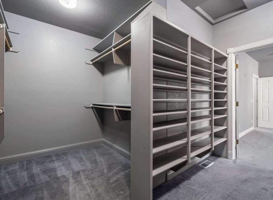 Discover ample storage in this spacious walk-in closet, featuring extensive shelving and hanging rods to organize your wardrobe.
