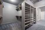 Discover ample storage in this spacious walk-in closet, featuring extensive shelving and hanging rods to organize your wardrobe.