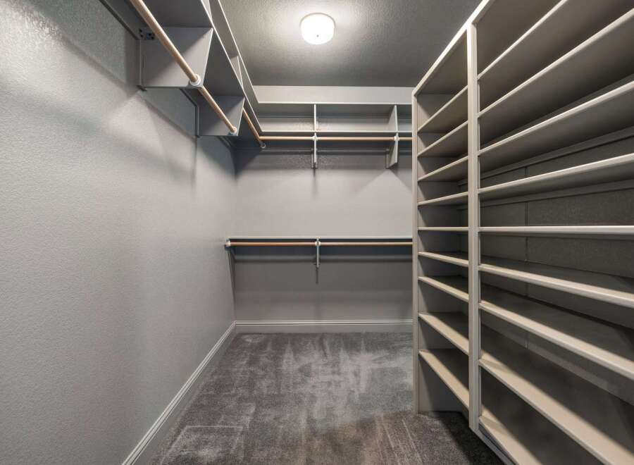 Step into this spacious walk-in closet, featuring ample shelving and multiple hanging rods to keep your wardrobe organized.