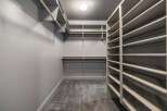 Step into this spacious walk-in closet, featuring ample shelving and multiple hanging rods to keep your wardrobe organized.