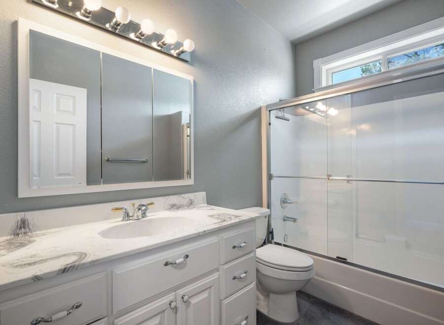 This bright and airy bathroom features a spacious vanity with a marble countertop and a large medicine cabinet with ample storage.