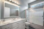 This bright and airy bathroom features a spacious vanity with a marble countertop and a large medicine cabinet with ample storage.
