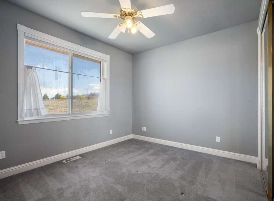 This spacious bedroom features a large window offering scenic views of the surrounding landscape.