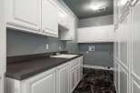 This laundry room boasts ample storage with a combination of upper and lower white cabinets, perfect for organizing supplies.