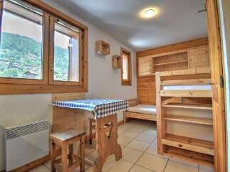 Experience cozy mountain living in this charming studio apartment, featuring a rustic wooden interior and large windows with scenic views.