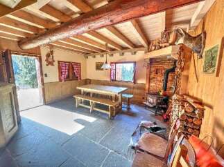 Experience rustic charm in this cozy mountain retreat, featuring a spacious dining area with a large wooden table and benches, perfect for gathering with loved ones.