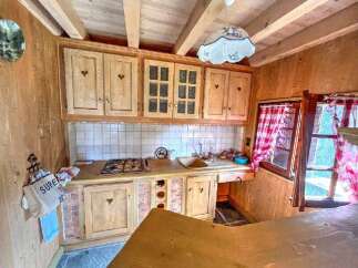 Discover this charming rustic kitchen featuring warm wooden cabinetry with heart-shaped accents and a classic tiled backsplash.